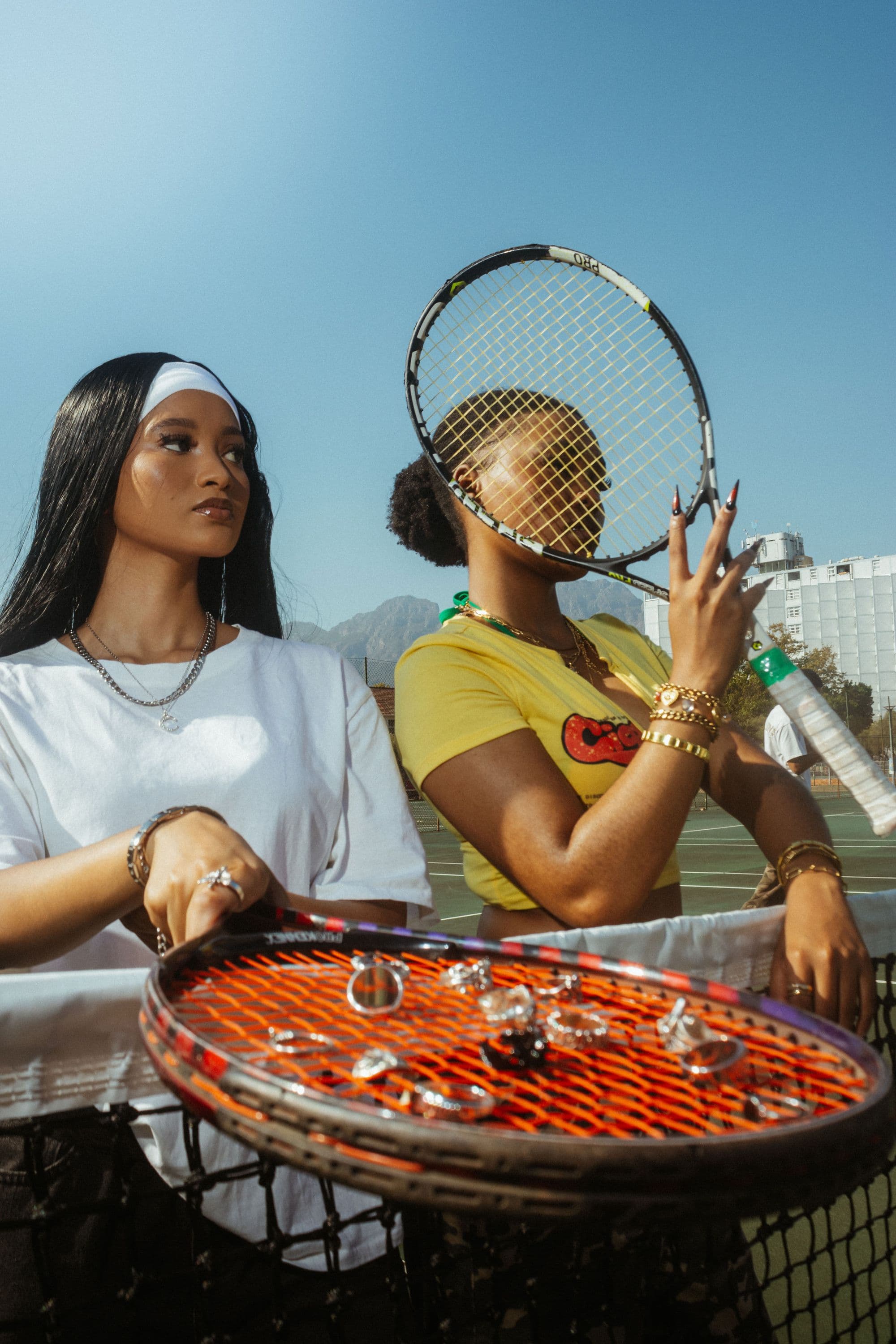 NEUXJEWELS pieces laid across a racquet on court